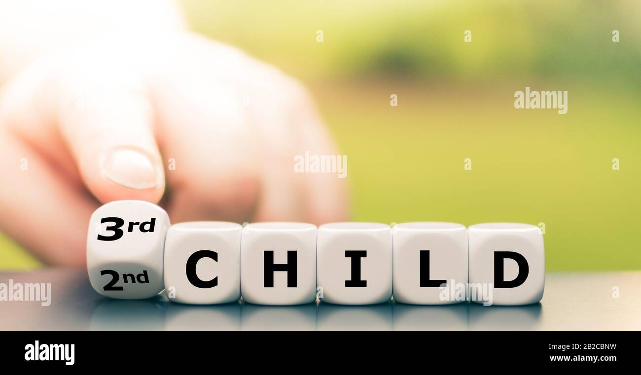 Ein drittes Kind erwartet. Die Hand dreht Würfel und ändert den Ausdruck "zweites Kind" in "drittes Kind". Stockfoto