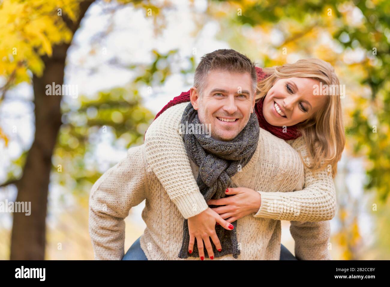 Portrait eines reifen attraktiven Mannes, der seiner Frau eine piggy Fahrt zurück in den Park beschritt Stockfoto