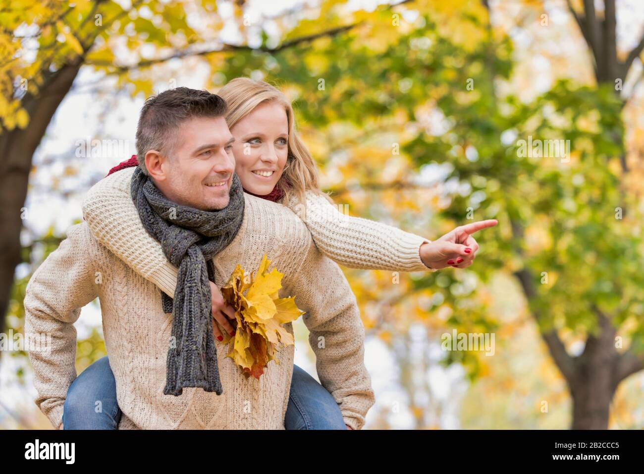 Portrait eines reifen attraktiven Mannes, der seiner Frau eine piggy Fahrt zurück in den Park beschritt Stockfoto