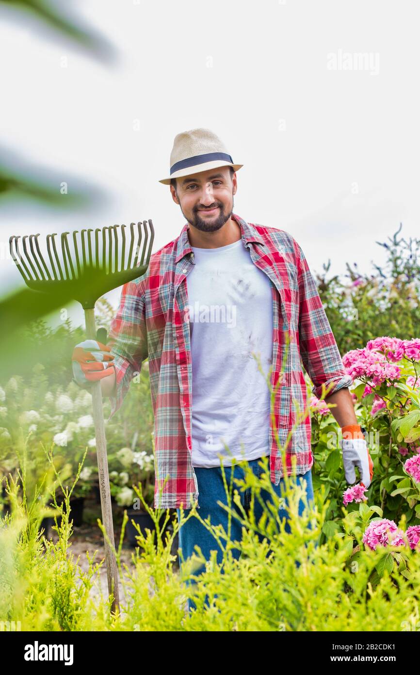 Porträt eines reifen Mannes, der Gabelrechen in der Gartenwerkstatt hält Stockfoto