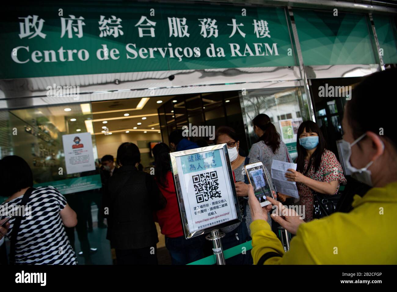 Macao, China. März 2020. Die Menschen scannen den QR-Code, um das Gesundheitsdokument auszufüllen, bevor sie in eine Regierungsdiensthalle in Macao, Südchina, am 2. März 2020 eindringen. Credit: Cheong Kam Ka/Xinhua/Alamy Live News Stockfoto