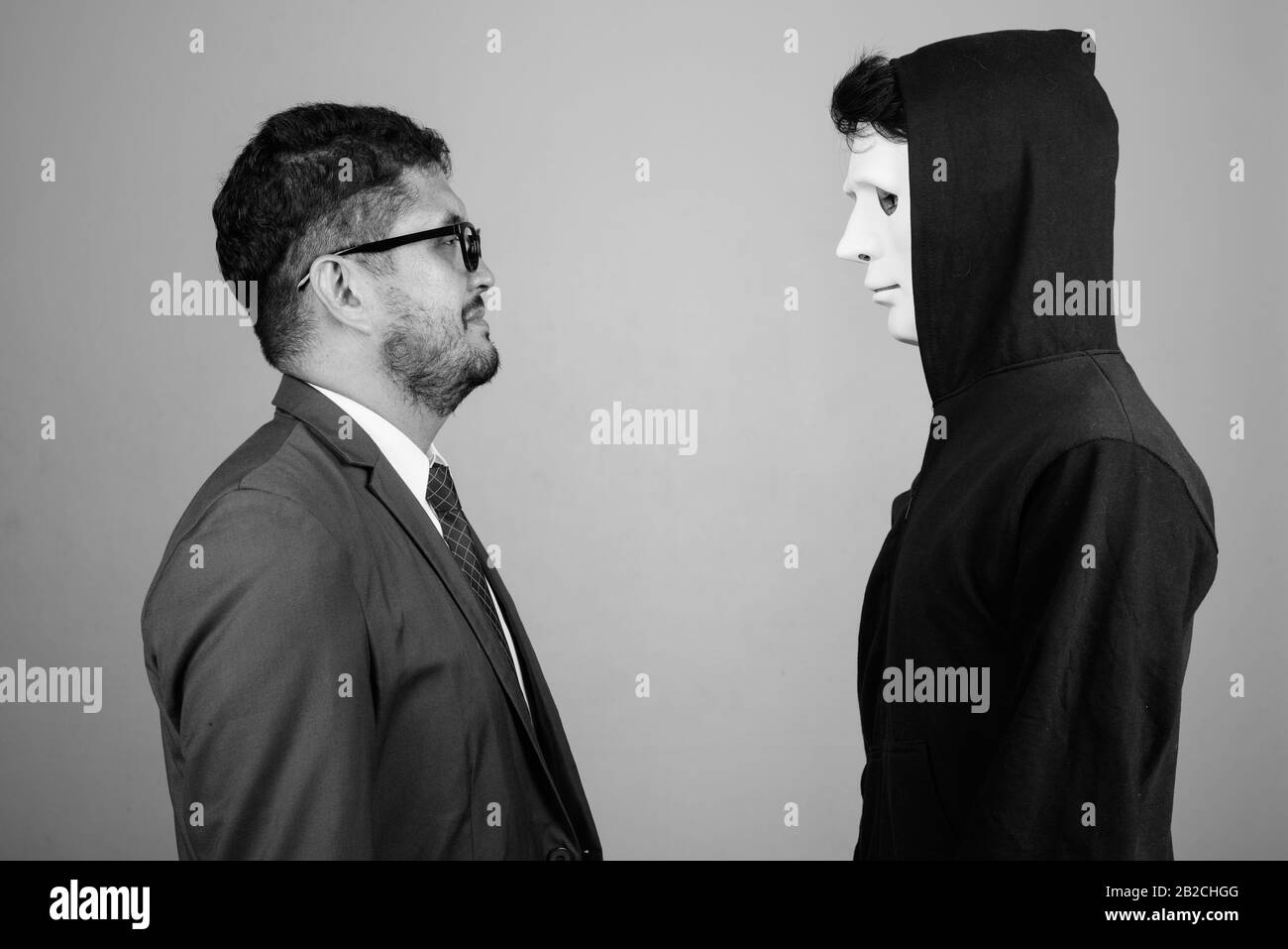 Bärtiger persischer Geschäftsmann und junger Indianermann vor grauem Hintergrund Stockfoto