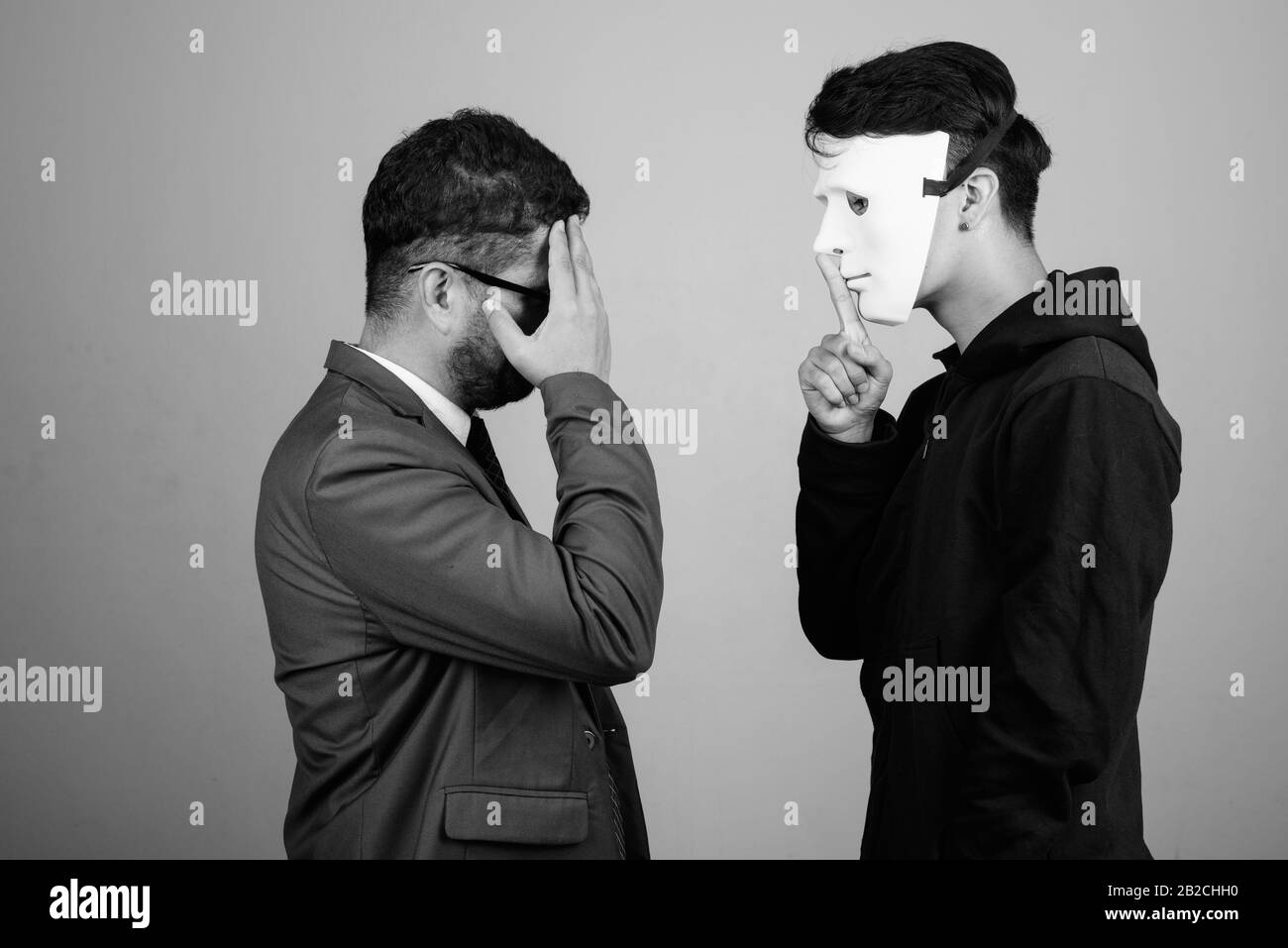 Bärtiger persischer Geschäftsmann und junger Indianermann vor grauem Hintergrund Stockfoto