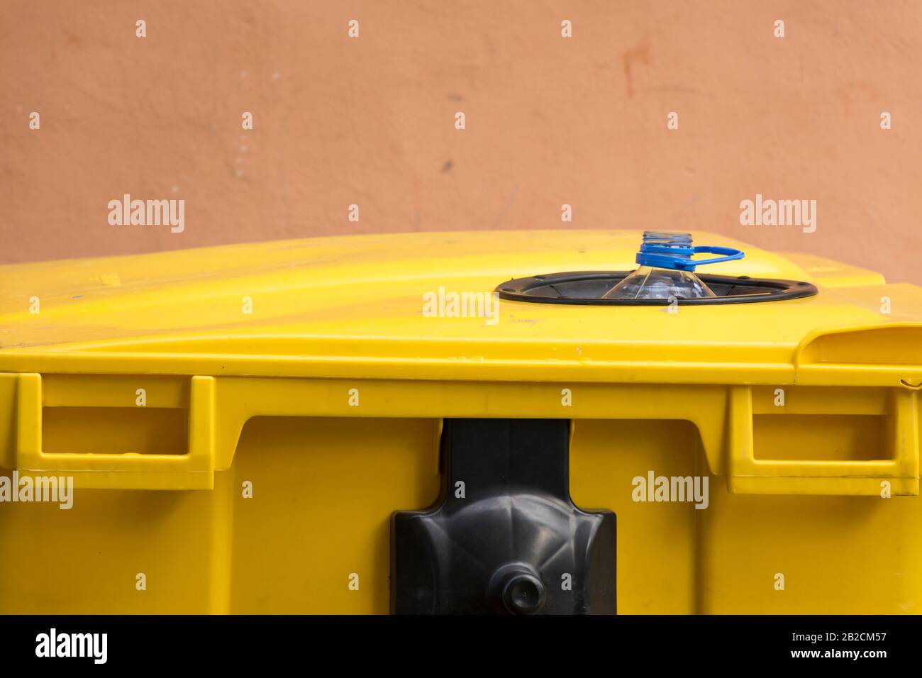 Eine Plastikflasche in einem vollen gelben Recyclingbehälter in der Stadt. Konzept der Pflege des Planeten Erde, Bildung, Bewusstsein und Recycling Stockfoto