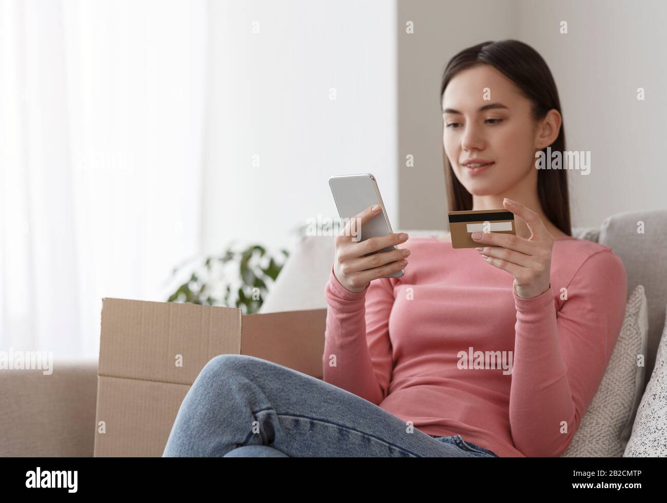 Frau mit Kreditkarte und Eingabe von Karteninformationen mit Handy Stockfoto