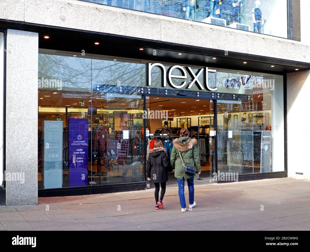 Eine Ansicht von zwei Kunden, die einen Next Store in Norwich, Norfolk, England, Großbritannien und Europa betreten möchten. Stockfoto