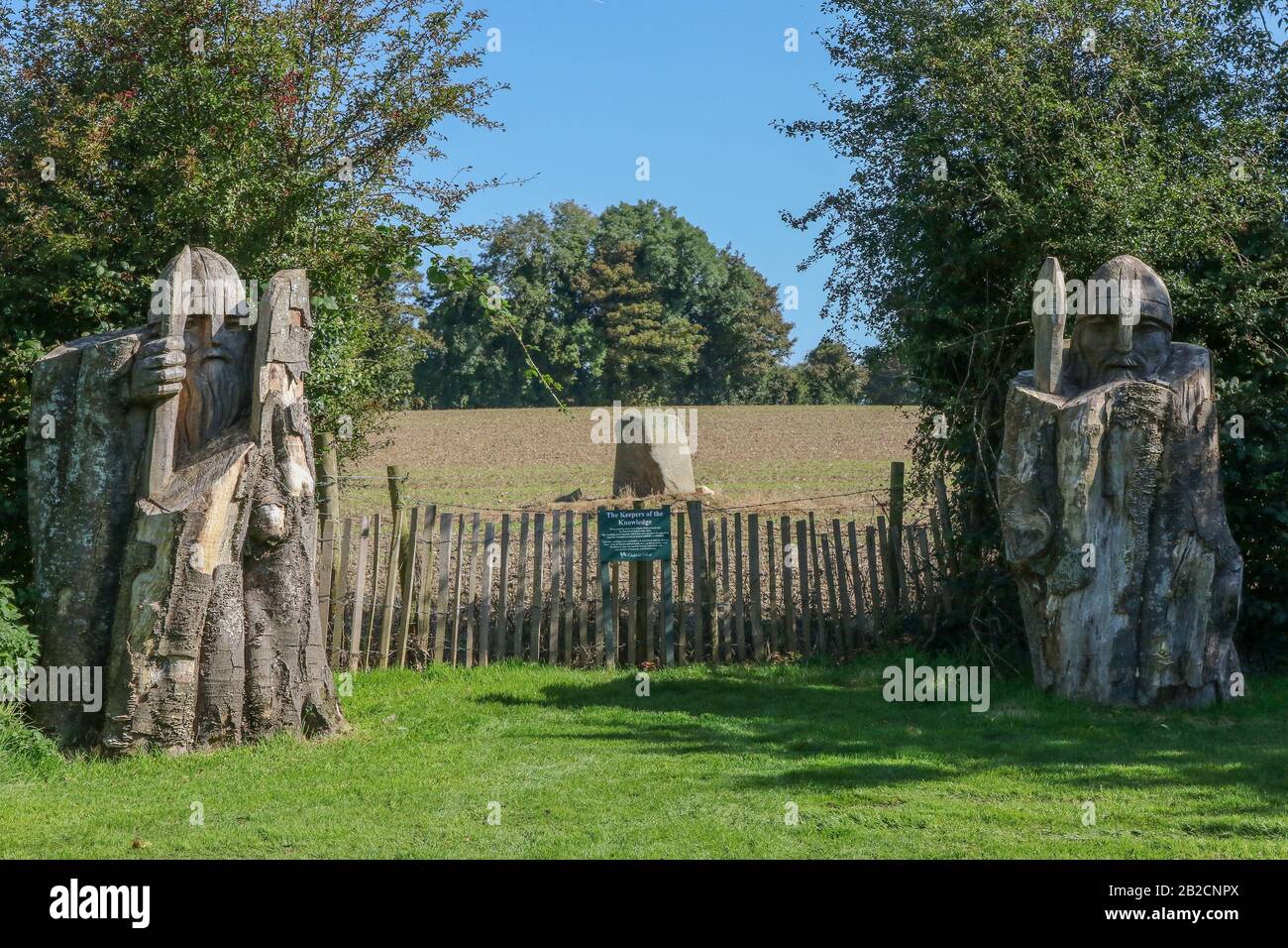 Altes neolithisches SteinIrland, geschützt durch Holzstatuen der "Keepers of Knowledge" in der benachbarten privaten Parklandattraktion des Oakfield Park. Stockfoto