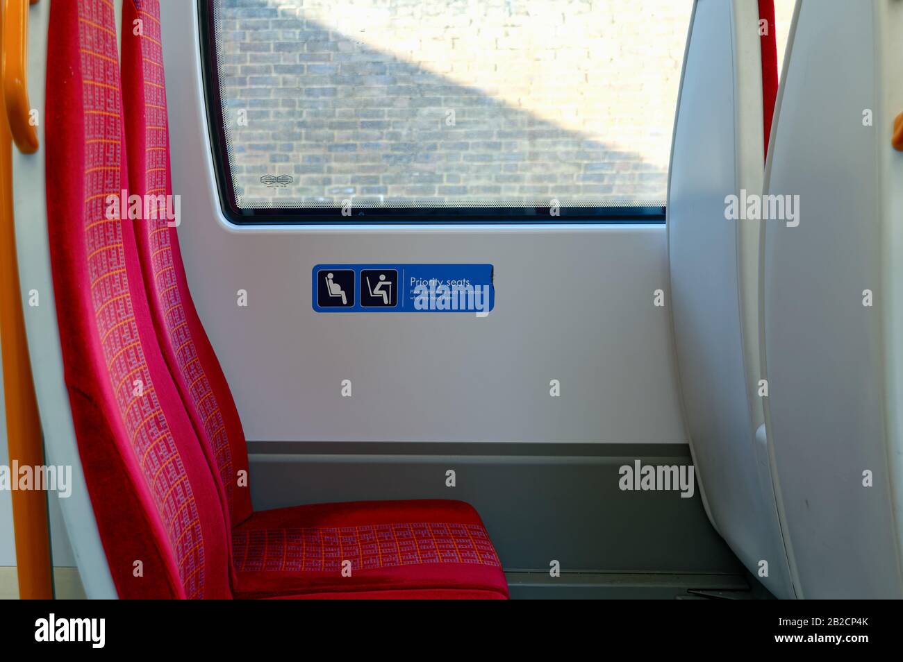 Nahaufnahme eines leeren Zugsitzes mit einem Schild mit der Aufschrift „bevorzugte Sitzplätze für ältere Menschen und alle, die sie benötigen könnten“, London England, Großbritannien Stockfoto