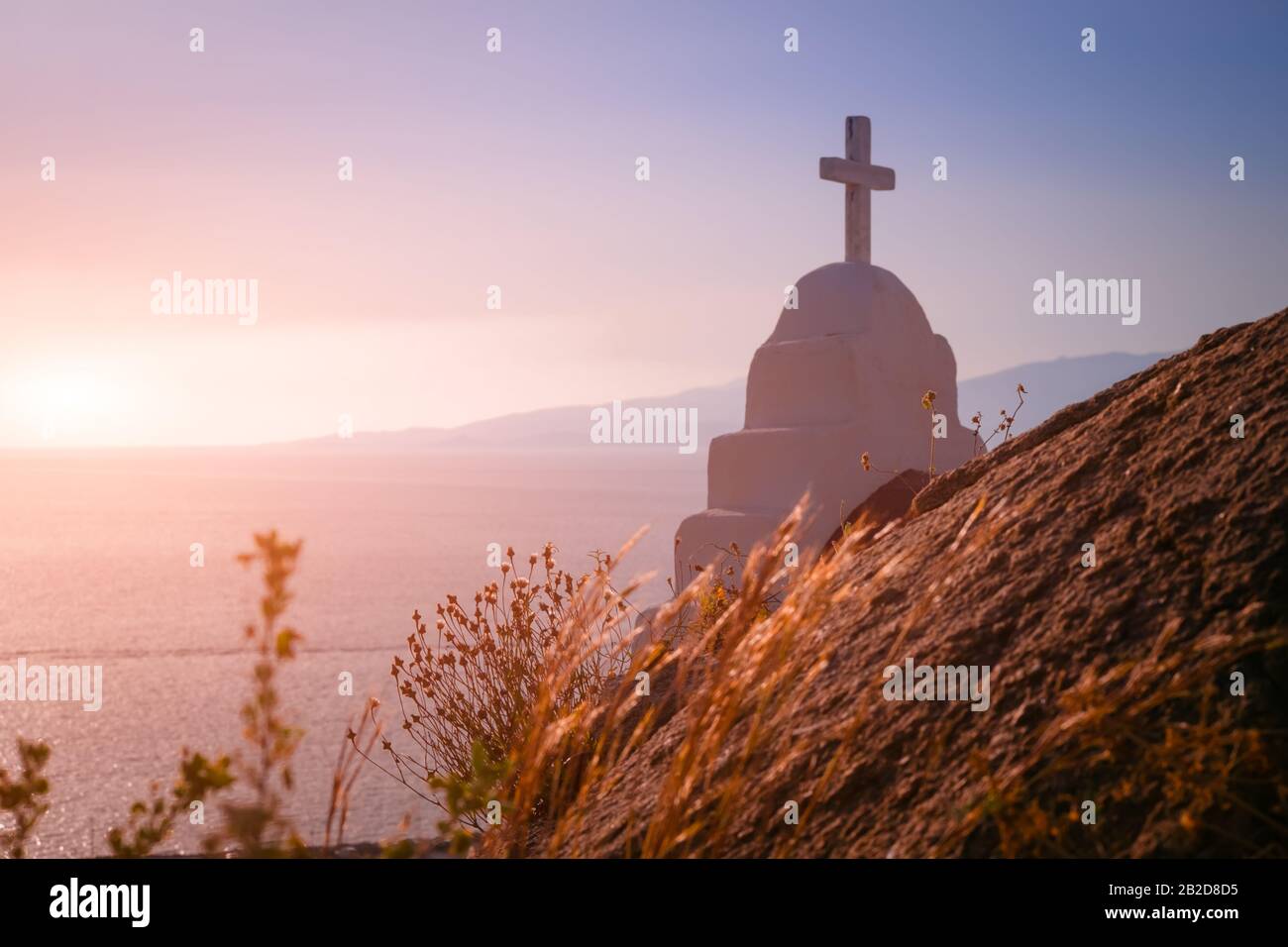 Fantastische Farben des ägeischen Meeres bei Sonnenuntergang. Orthodoxen Kirchenkreuz, christentumsreligionssymbol. Insel Mykonos. Griechenland Stockfoto