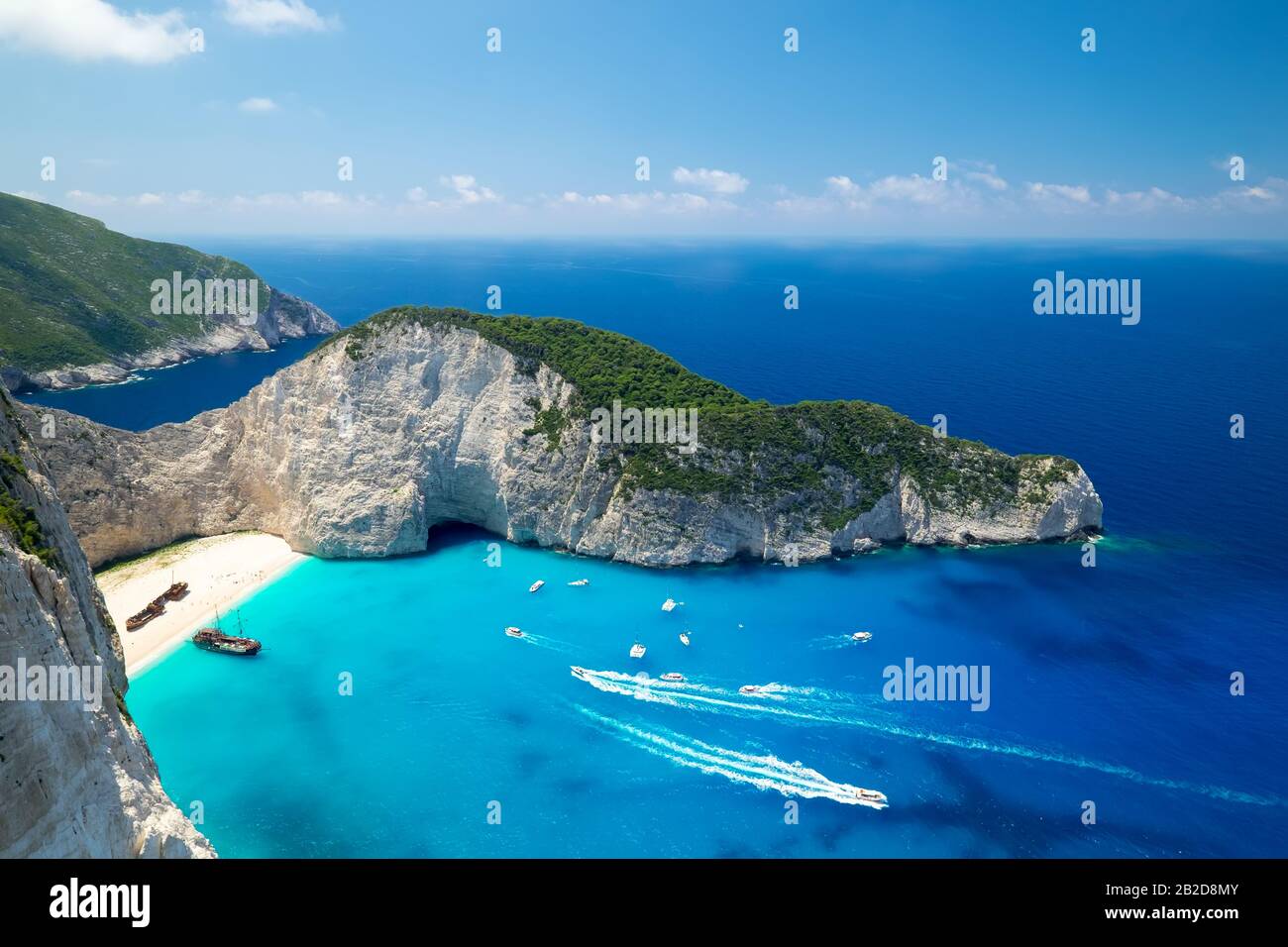 Malerischer Draufsicht auf Navagio Beach oder Shipwreck Beach. Altes Schiff nach dem Absturz auf Sand in der Lagune, umgeben von hohen Felsen. Boote, die türkis Schwimmen Io Stockfoto