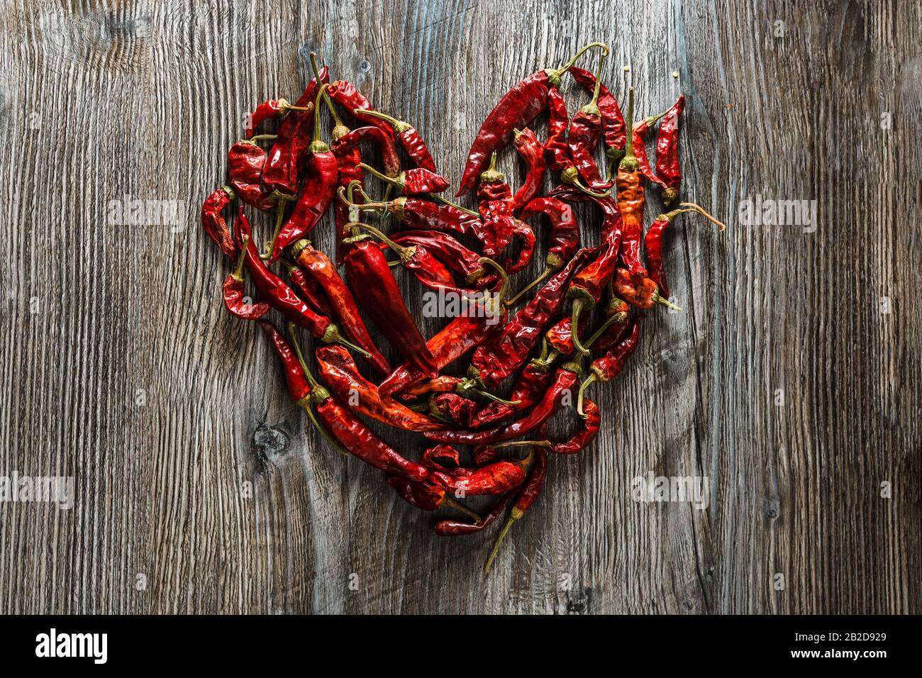 Mexikanische Küche. Getrockneter roter heißer Chili Pfeffer in Form eines Herzens auf Holzgrund. Würziger Geschmack Stockfoto