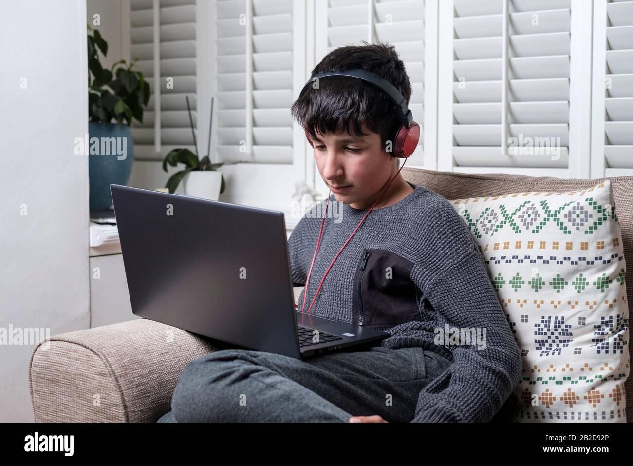 Junge Teenager im Alter von 13 Jahren wachen Online-Videos auf einem Laptop zu Hause Stockfoto
