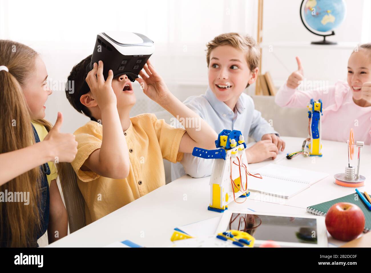 Fröhlicher Schuljunge mit VR-Brille bei Technologieunterricht Stockfoto