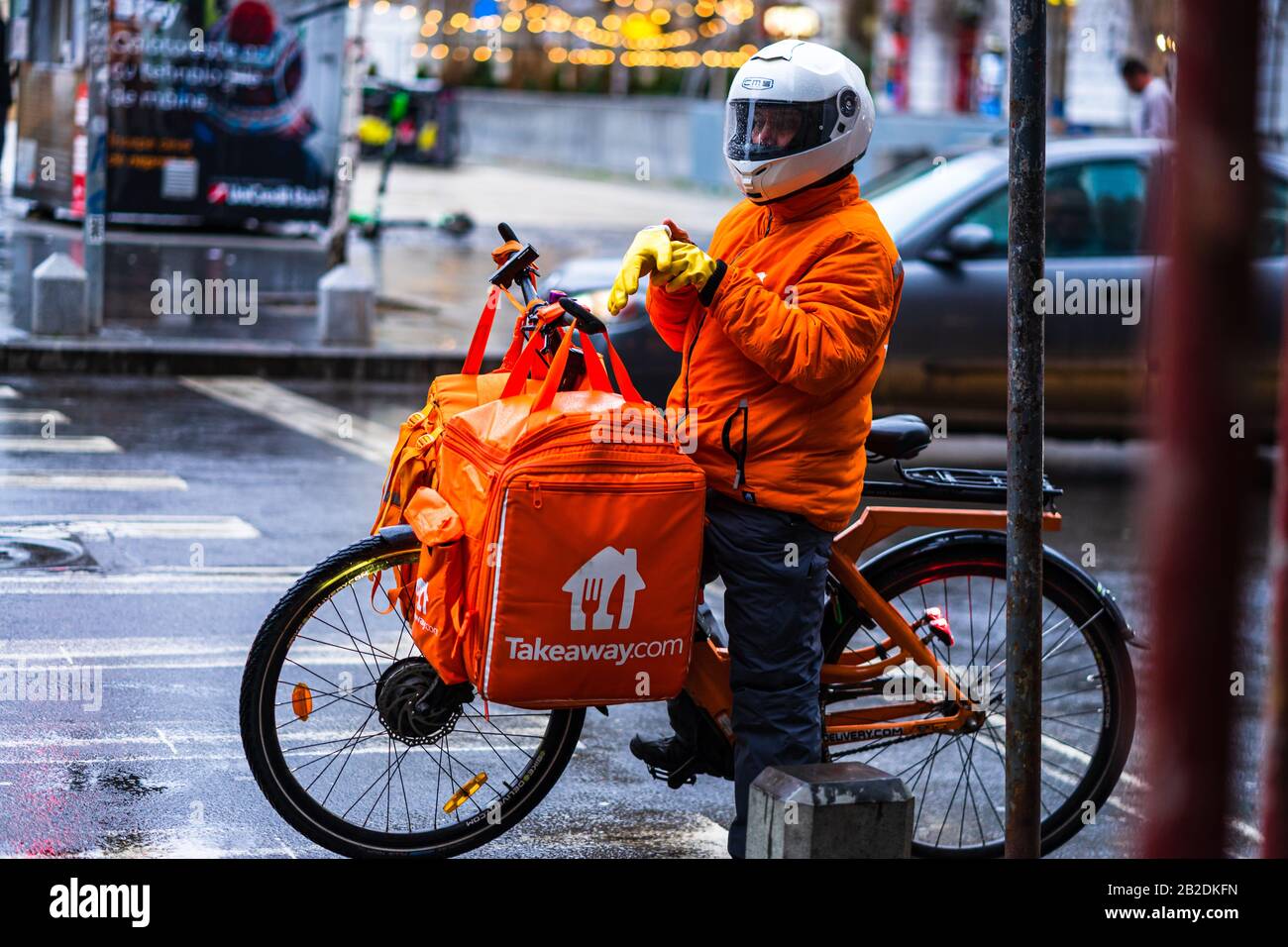 Junger Mann auf einem Elektrobike mit takeaway.com Logo, der während eines regnerischen Tages in Bukarest, Rumänien, 2020 Essen liefert Stockfoto