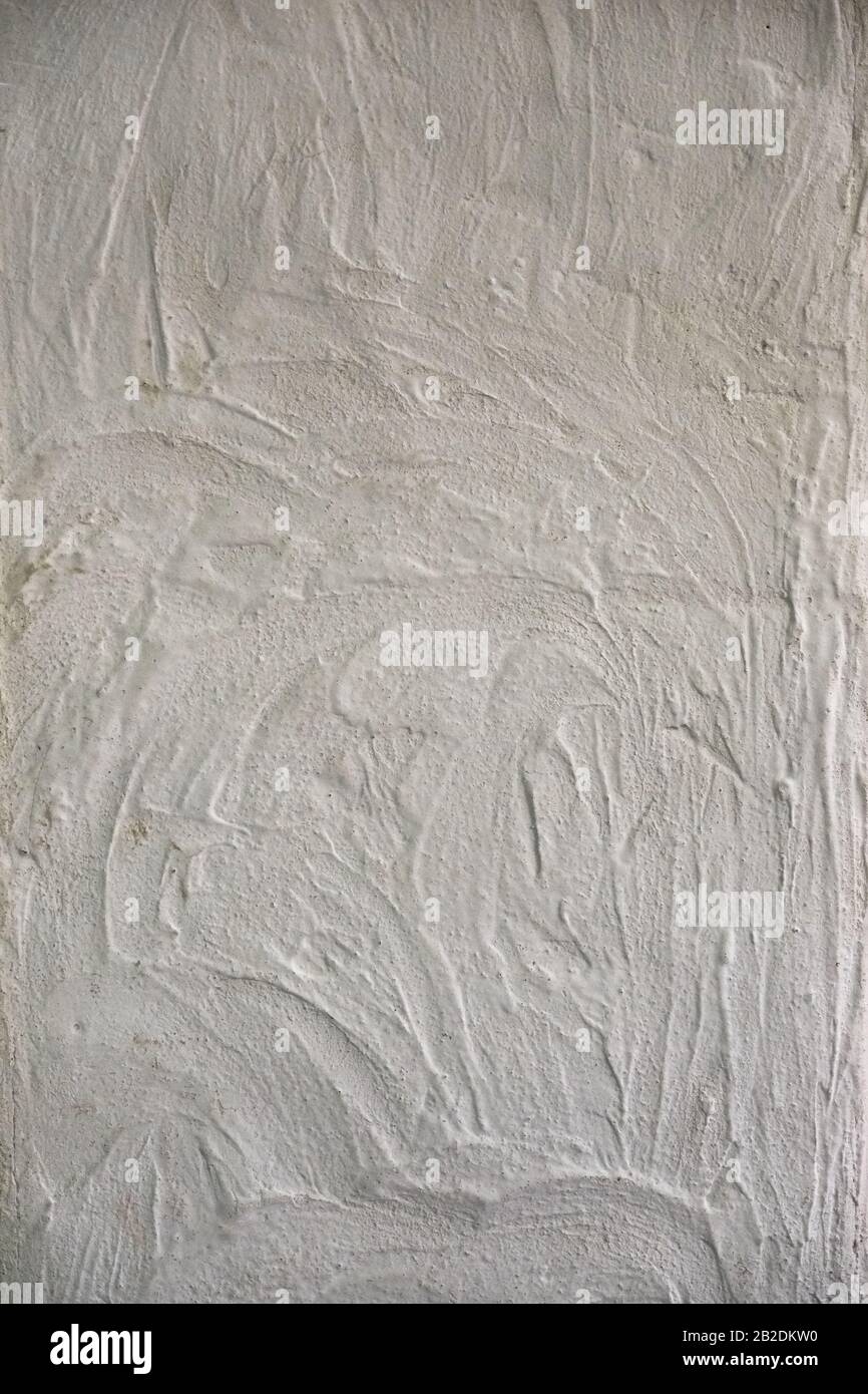 Weiße, strukturierte Wand mit wellenartigen Flecken. Texturhintergrund. Stockfoto