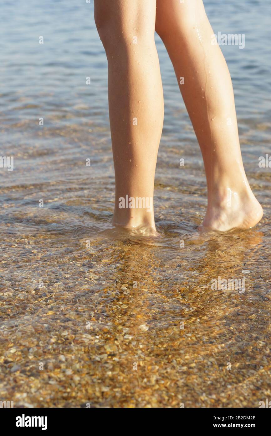 Füße im kristallklaren Meerwasser. Die Unterseite mit der Schale. Seitenansicht Stockfoto