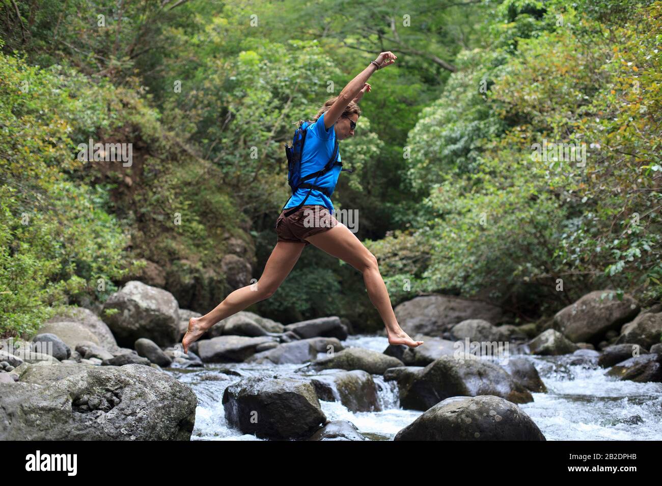 Woman Hiker springt mitten in den Rock, Iao Valley State Park, Maui, Hawaii. Stockfoto