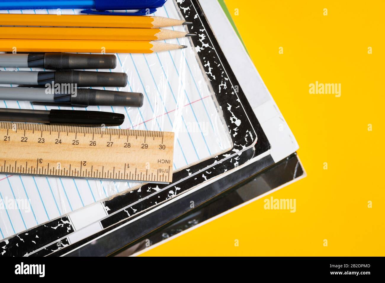 Schulbücher und Verbrauchsmaterialien auf gelbem Hintergrund Stockfoto