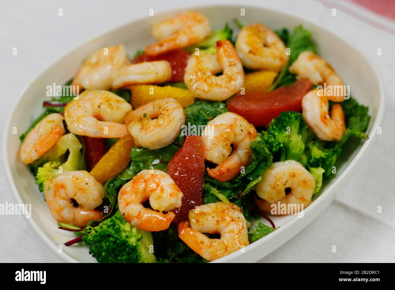 Gegrillter marinierter Shrimp-Salat mit Orange, Brokkoli und Salatblättern mischen Stockfoto