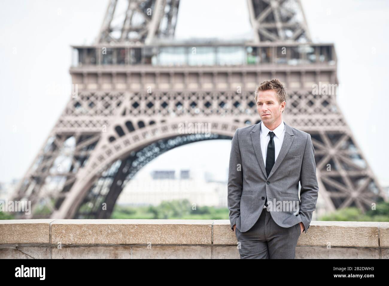 Der ernsthafte europäische Geschäftsmann steht allein vor dem Eiffelturm in Paris, Frankreich Stockfoto
