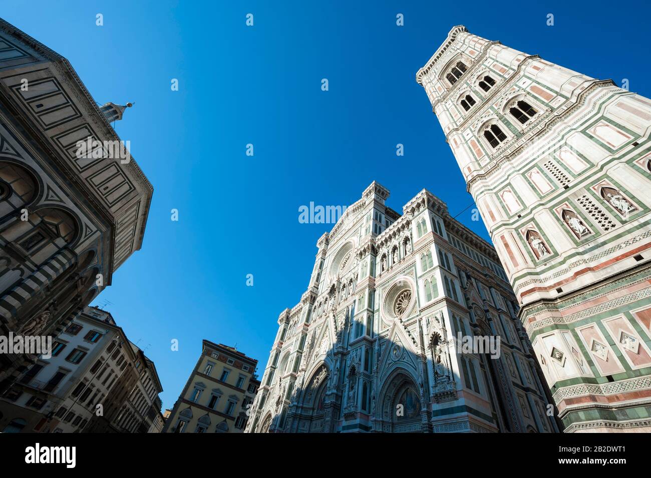 Dramatischer Chiaroscuro-Blick auf die Piazza del Duomo mit dem Portal und dem Turm der Kathedrale gegen den hellblauen Himmel in Florenz, Italien Stockfoto