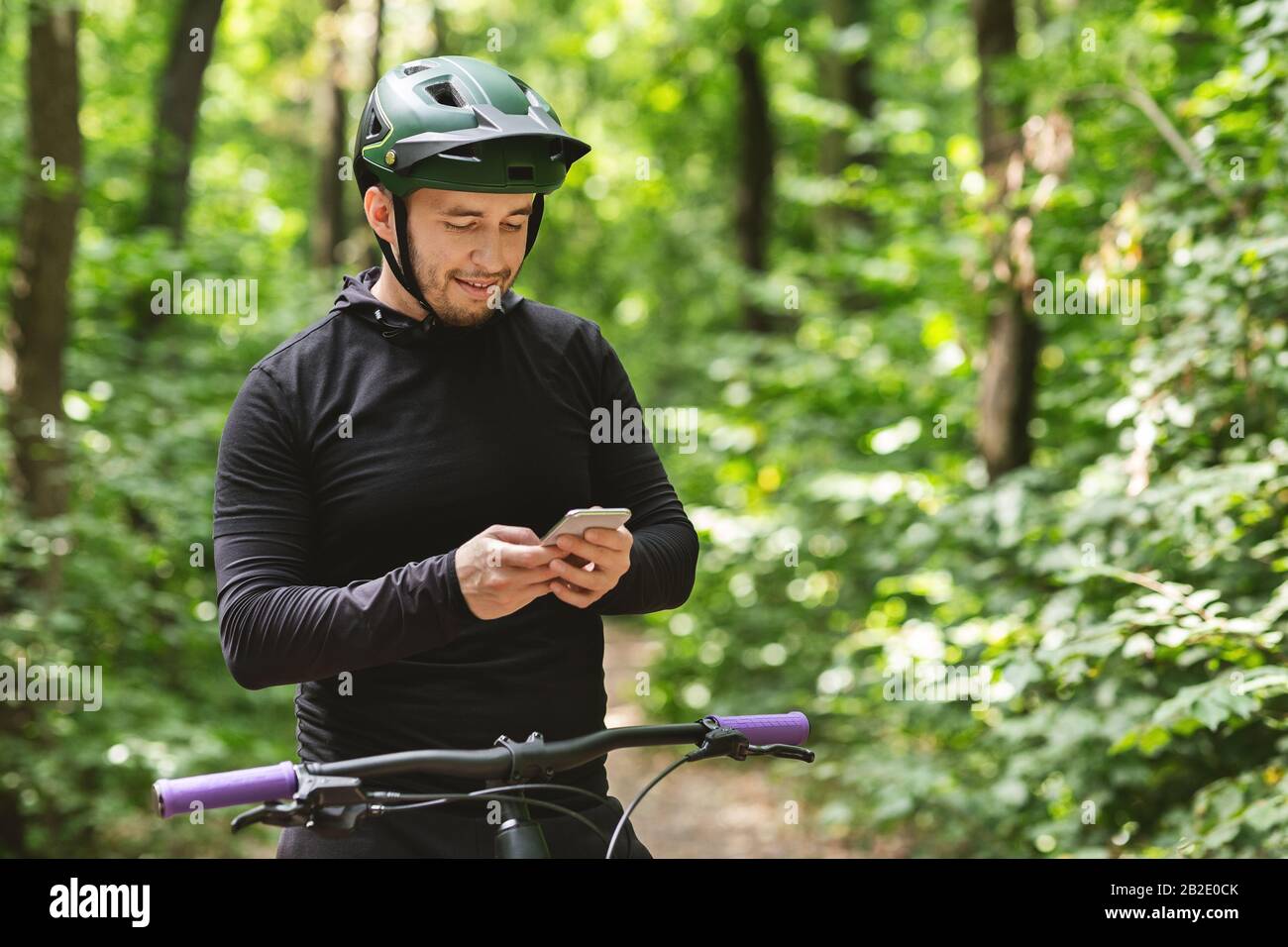 Glücklicher Radfahrer hält Smartphone, prüft Nachrichten Stockfoto