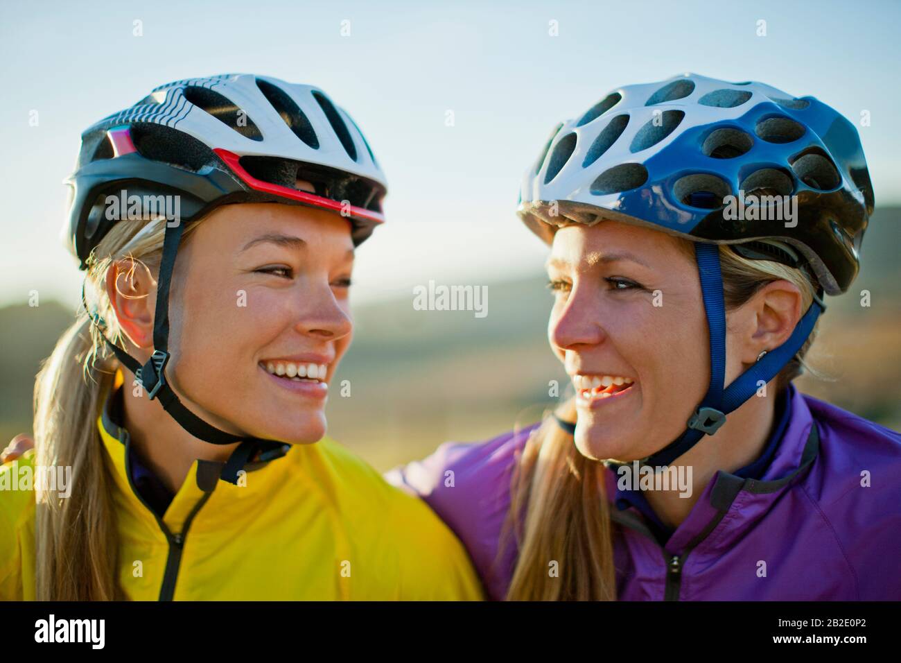 Zwei junge Frauen lächeln miteinander und machen eine Pause vom Fahrradfahren auf dem Land Stockfoto
