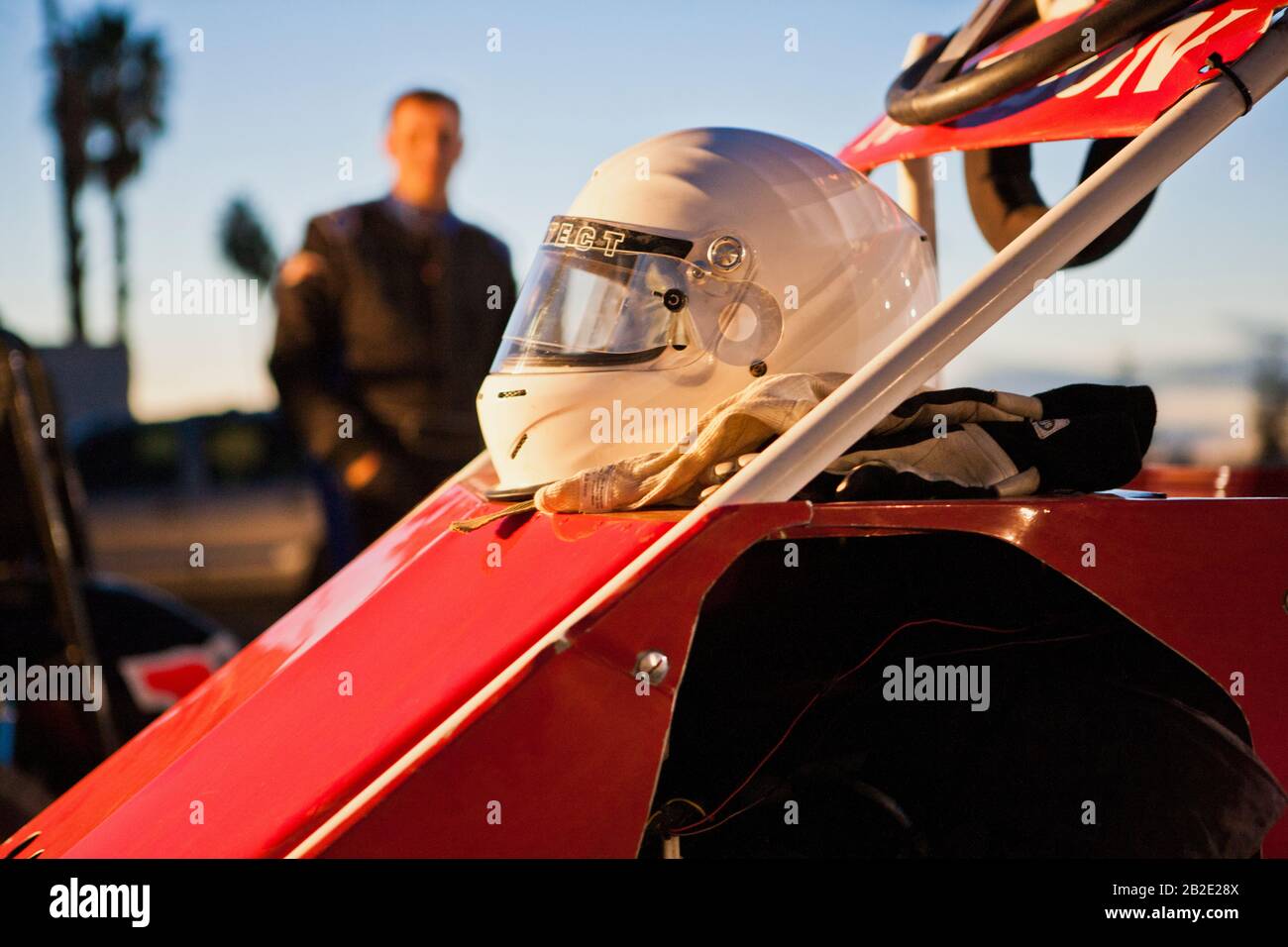 Porträt eines Rennfahrers, der hinter seinem Auto und Helm steht Stockfoto