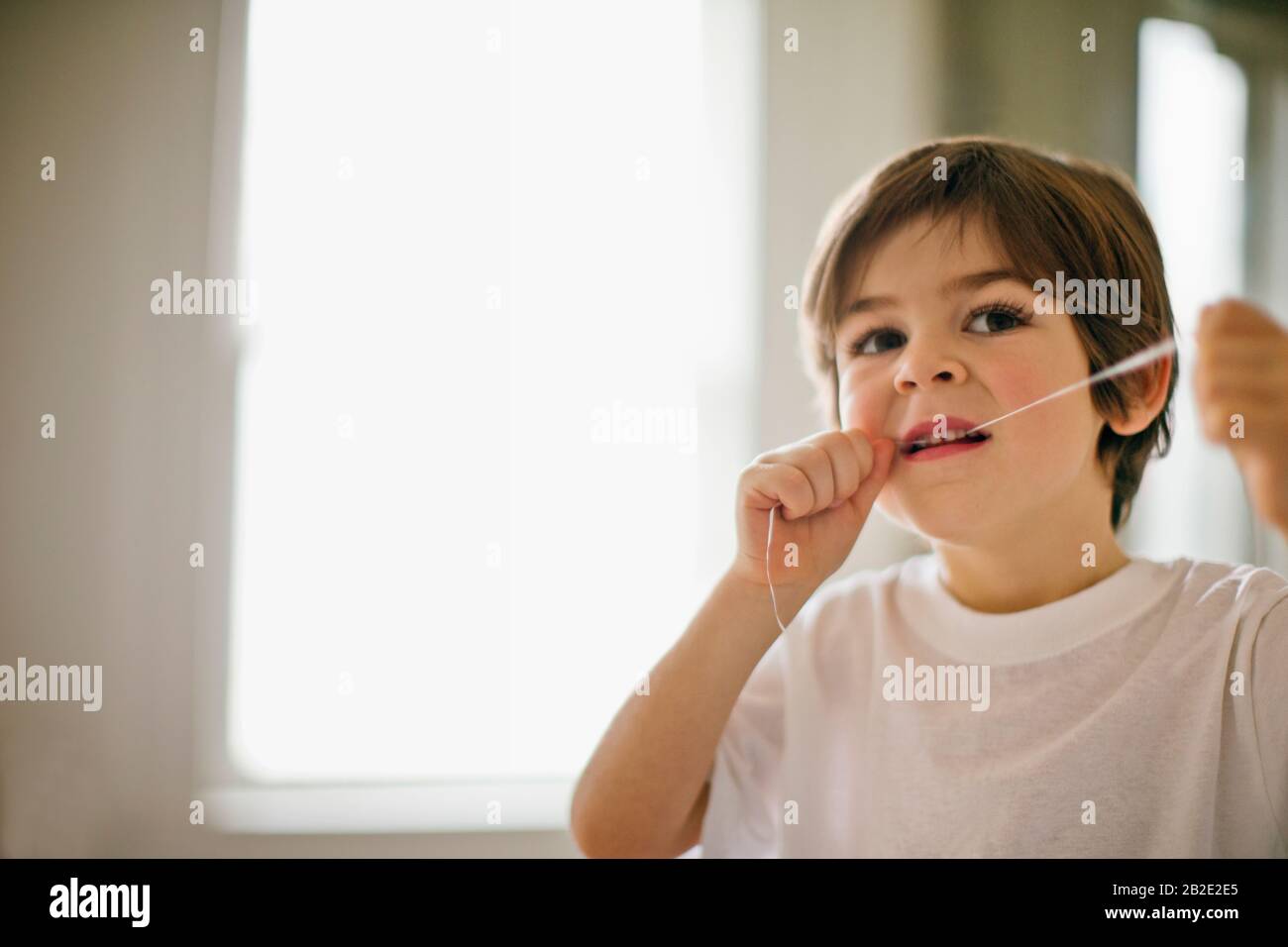 Der junge Junge flossing seine Zähne. Stockfoto