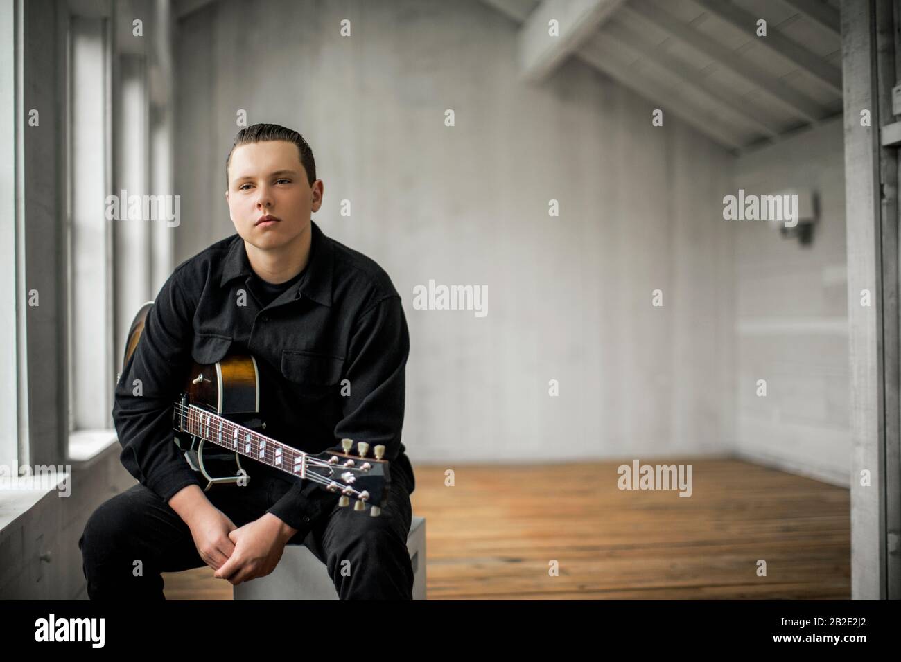 Porträt eines Teenagers, der mit seiner E-Gitarre sitzt Stockfoto
