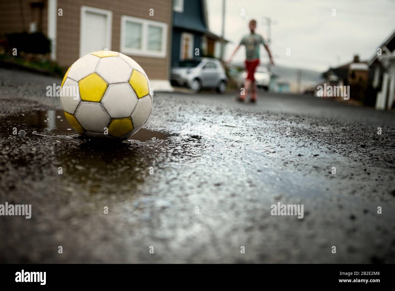 Junge, der mit einem Fußballball auf der Straße spielt Stockfoto