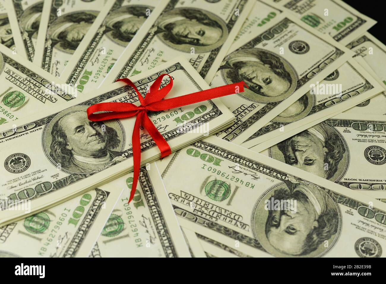 Hintergrund einer Menge Geldscheine 100 Dollar kanadischen Amerikaner in einem Stapel mit rotem Bogen, der eine Lotterie mit einem Geschenkgeschenk gewinnt Stockfoto