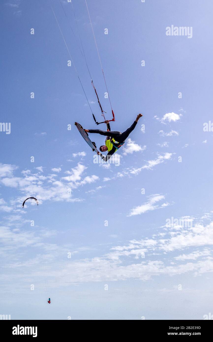 Kiteboarder Dimitri Maramenides macht aus einem sauberen Sprung Tricks in der Luft über den Kopf. Stockfoto