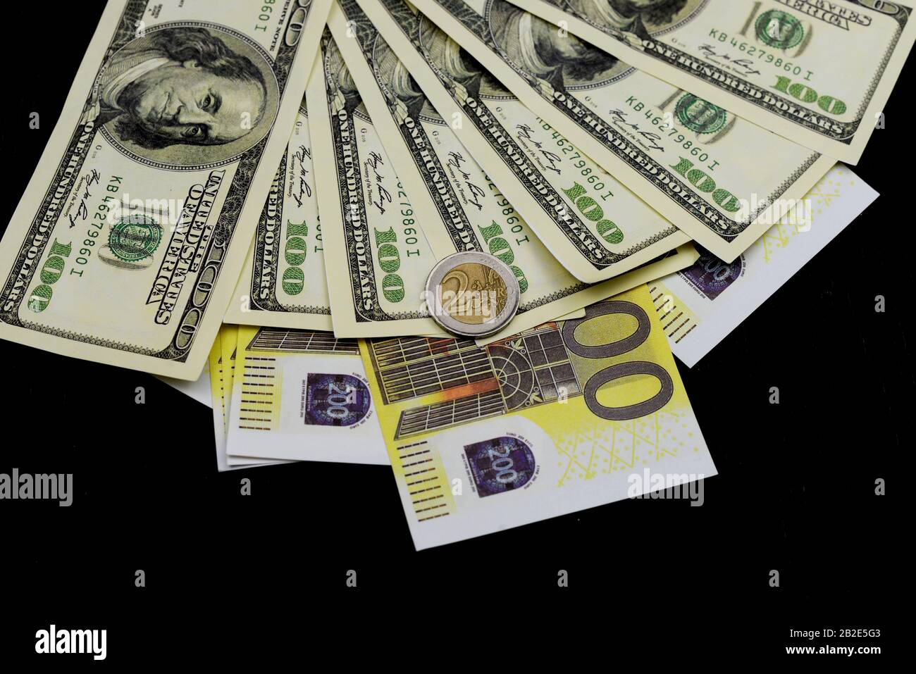 Euro-Münze mit Dollarscheinen und Banknoten auf schwarzem Hintergrund für Wirtschaft und Finanzen Stockfoto