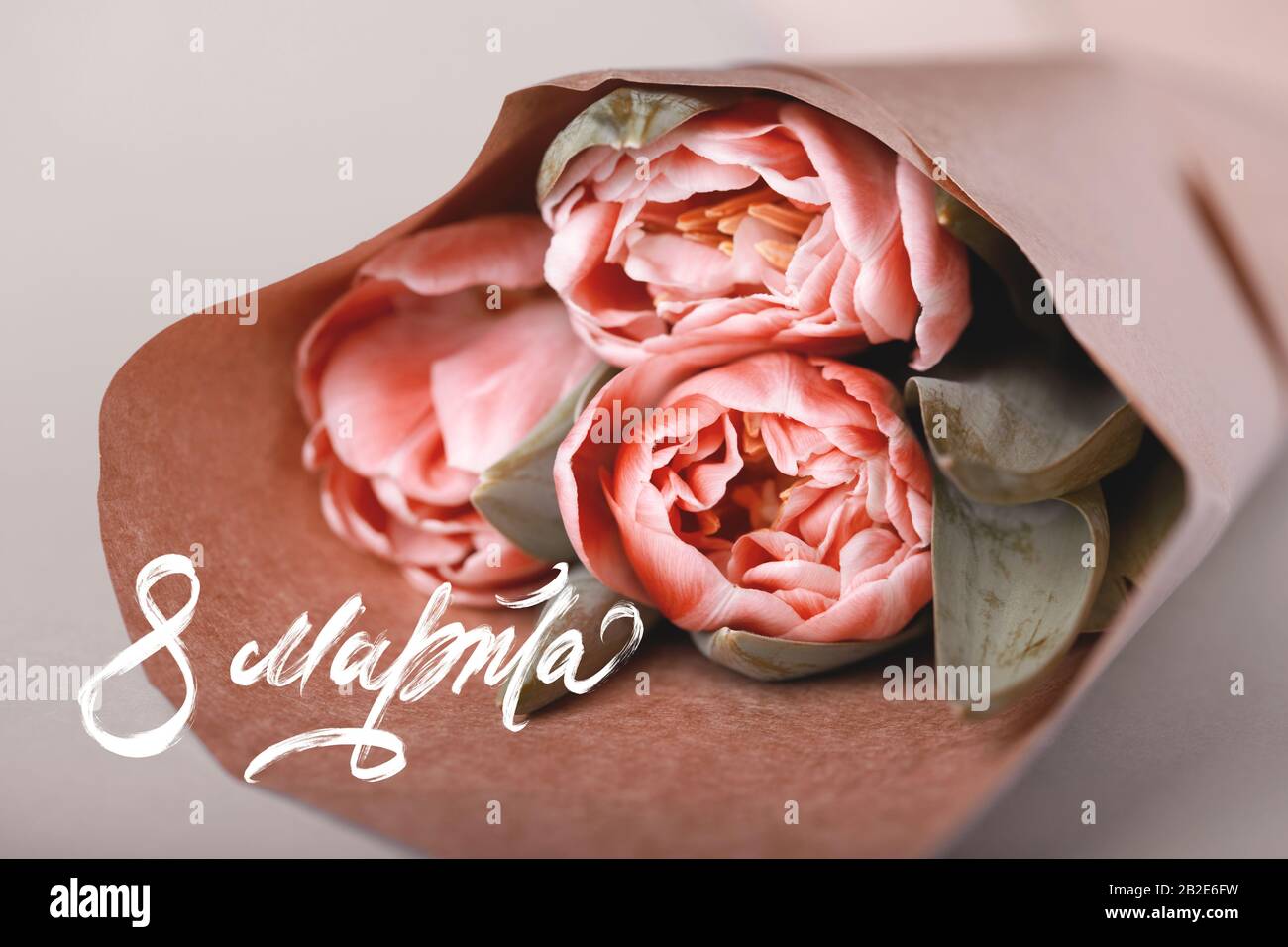 8. März - Grußkarte für den internationalen Frauentag mit einer Aufschrift  auf Russisch. Auf einem Tisch liegt ein Blumenstrauß aus drei Tulpen in  einem Papierwickler Stockfotografie - Alamy