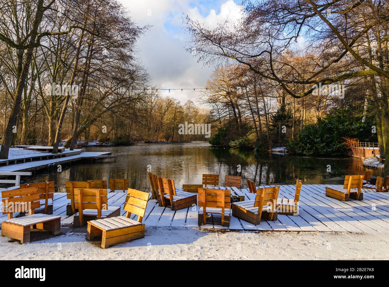 Landschaft von gefrorenen See, Schneedecke Holzstühle im Freien, Sitze und Terrasse am Wasser und Wald in Winteratmosphäre. Stockfoto