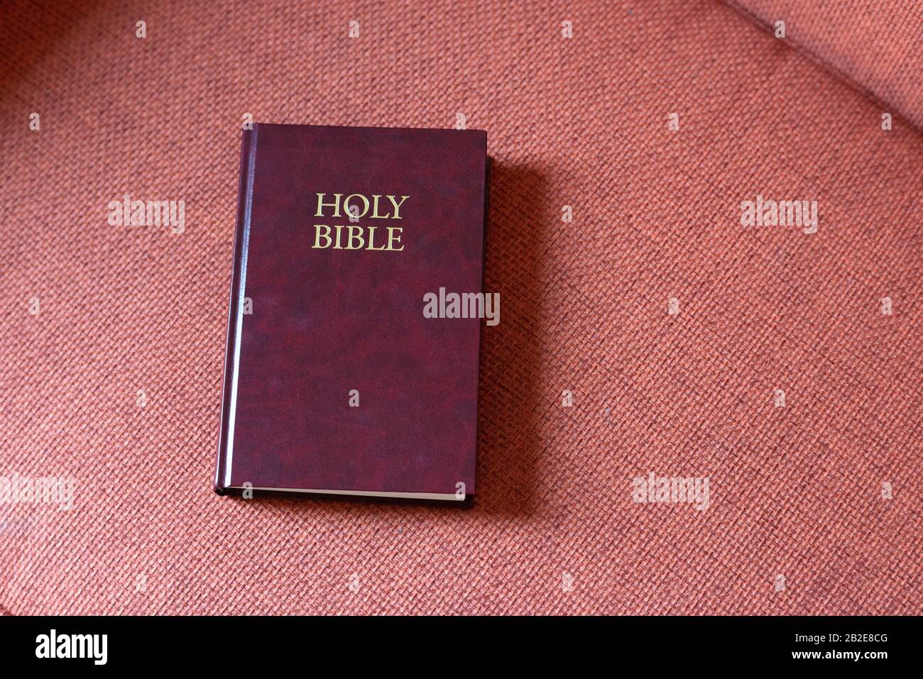 Heilige Bibel auf korallenfarbenem Stuhl im Motelzimmer Stockfoto