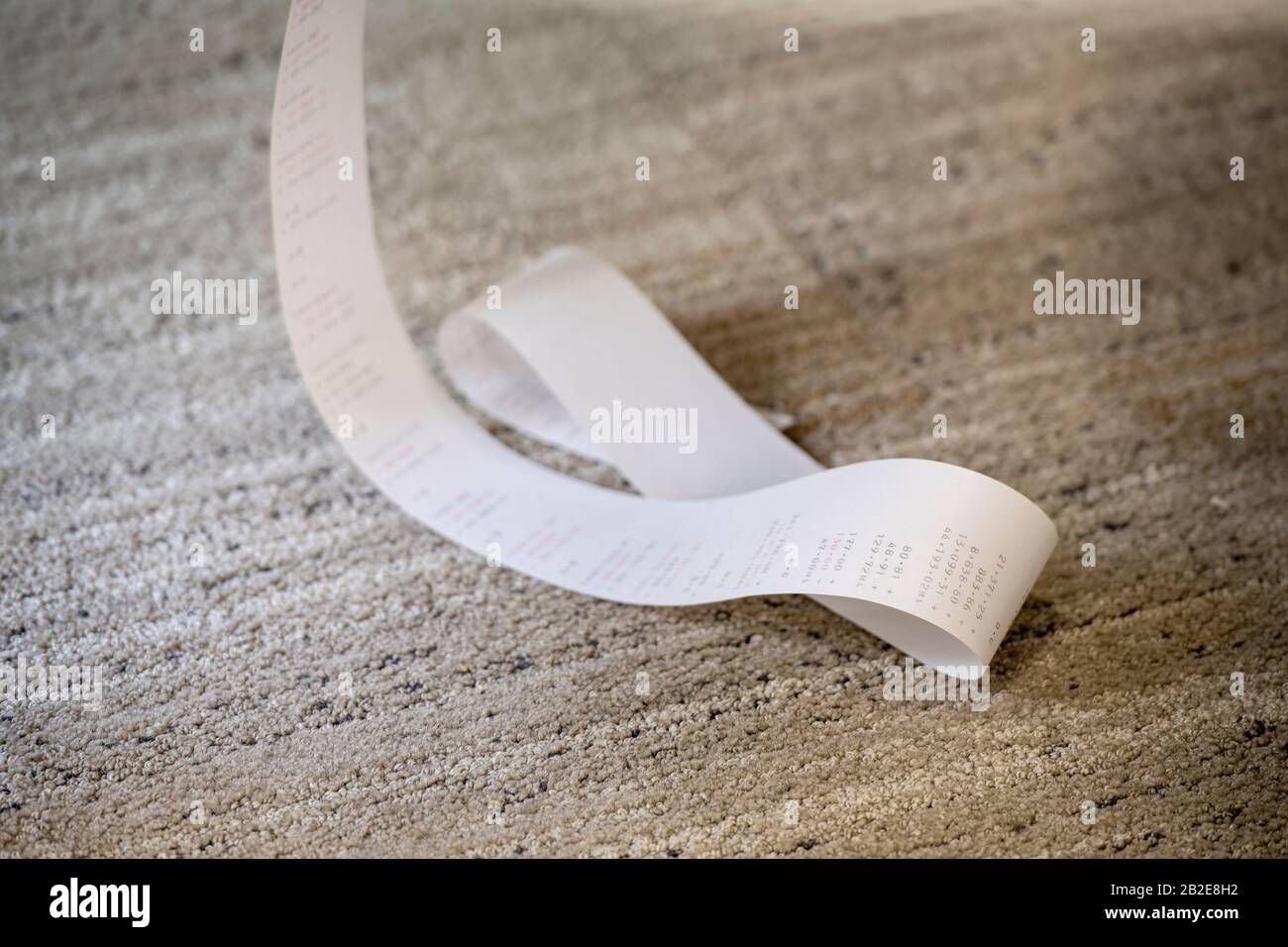 Hinzufügen von Papierband aus der Maschine, das auf dem Teppichboden gesammelt wurde Stockfoto