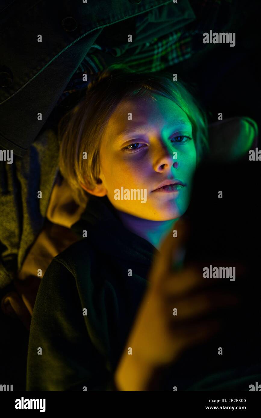 Porträt von Tween Blick auf Tablette mit buntem Licht auf Gesicht Stockfoto