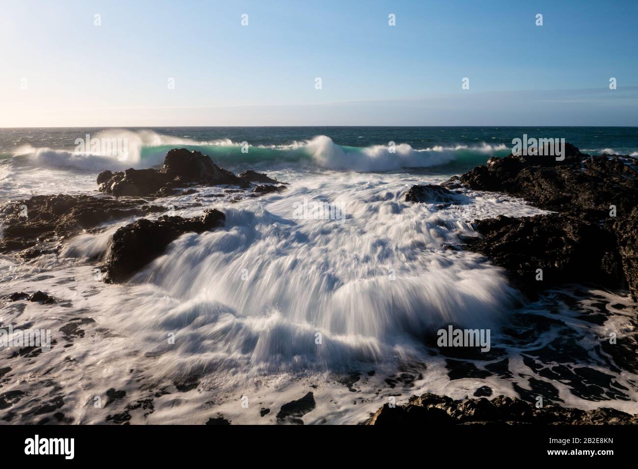 Wellen, die bei Flut über Gezeitenbecken und Küstenfelsen wuschen Stockfoto