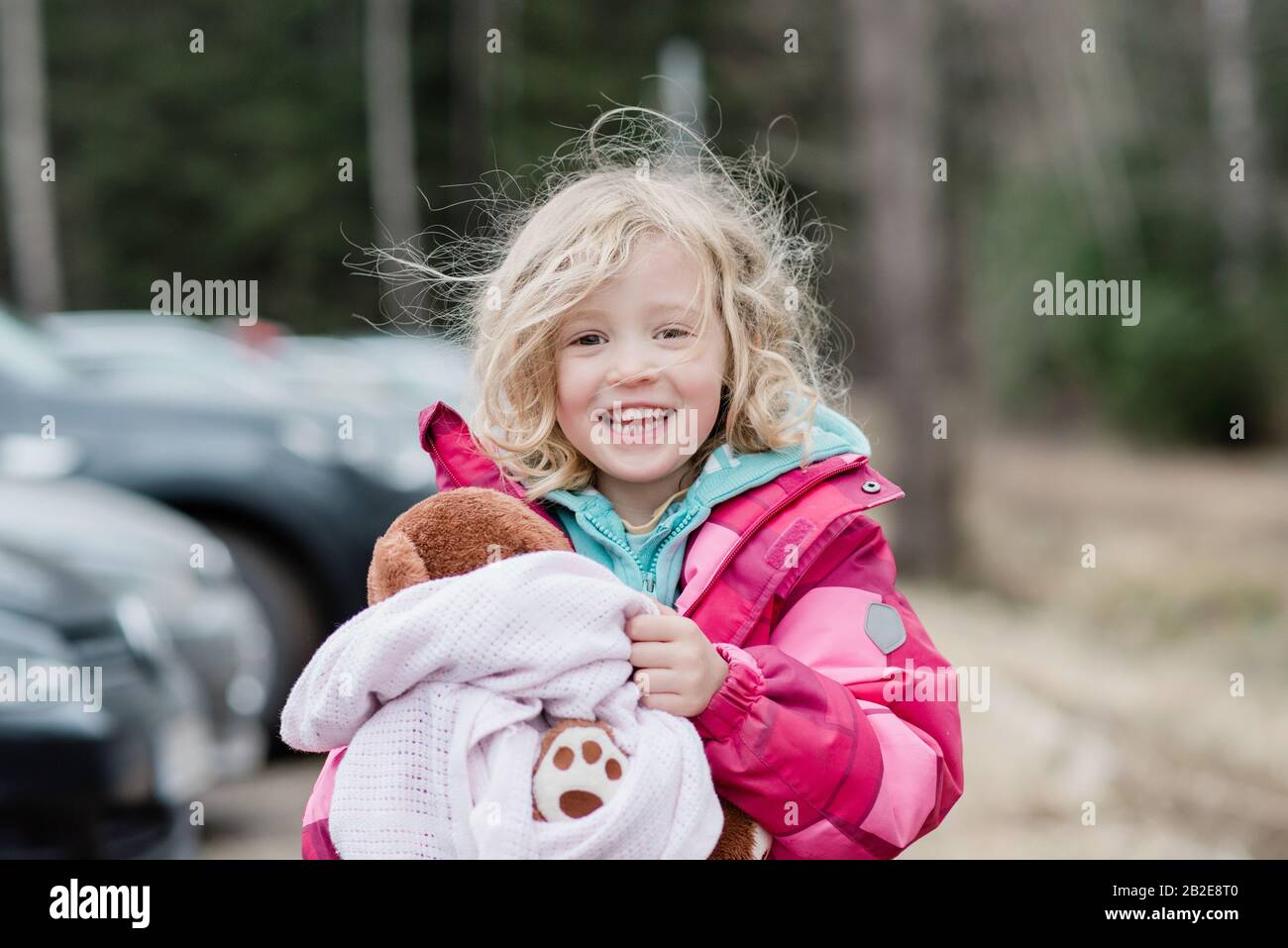 Ehrliches Porträt eines jungen Mädchens, das mit unordentlichen Haaren und Bettdecke lächelt Stockfoto