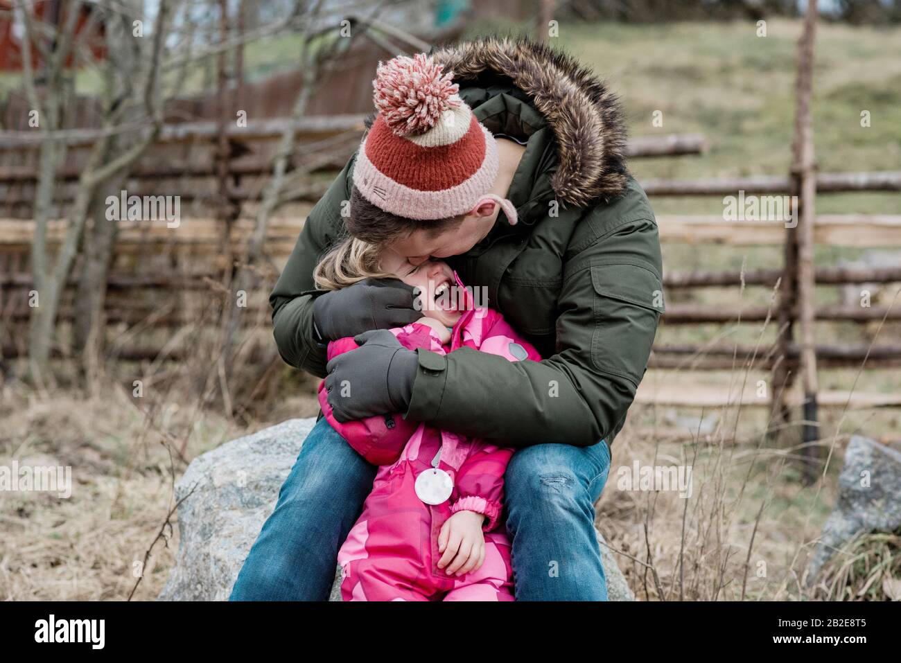 Ehrliches Porträt des verspielten Vaters küsst seine Tochter draußen Stockfoto