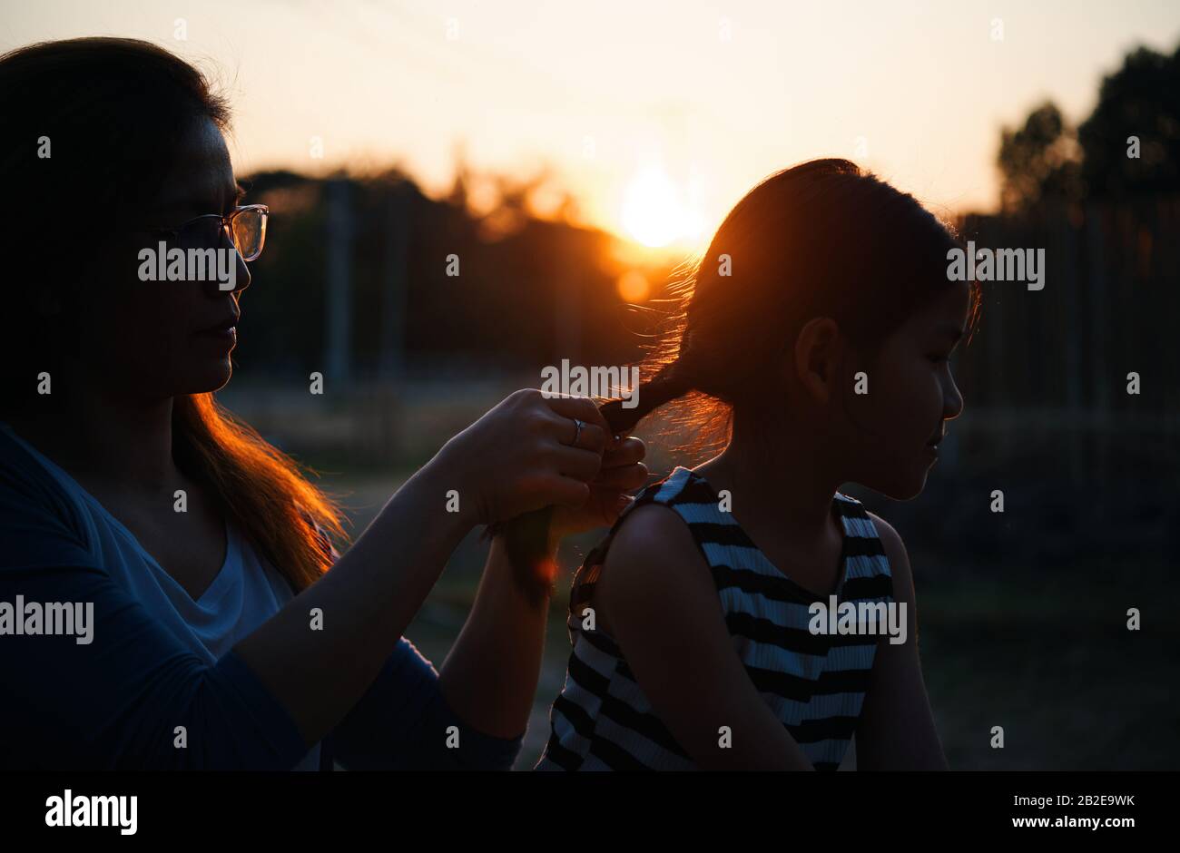 Die Mutter styling die Haare ihrer Tochter während des Sonnenuntergangs Stockfoto