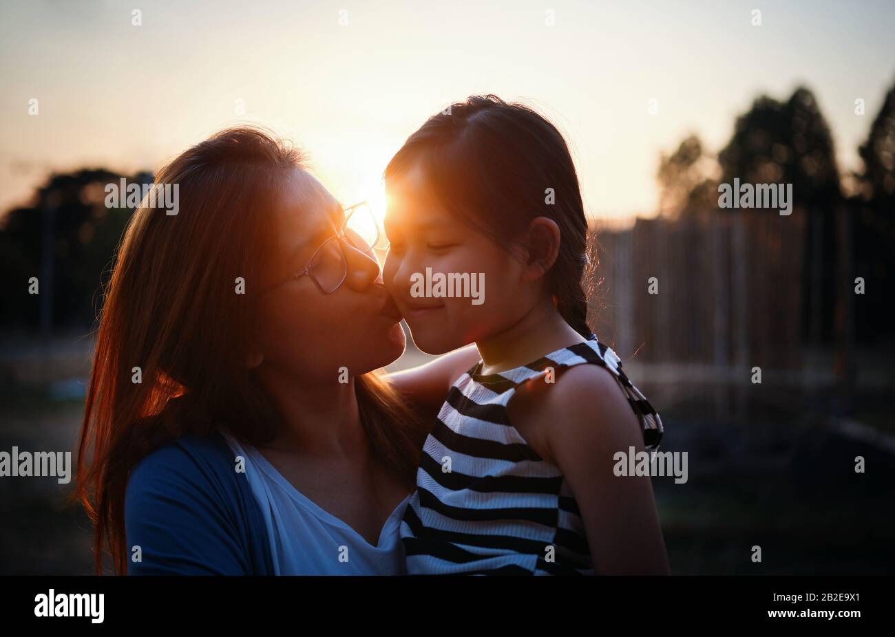 Mutter küsst ihre Tochter während des Sonnenuntergangs Stockfoto