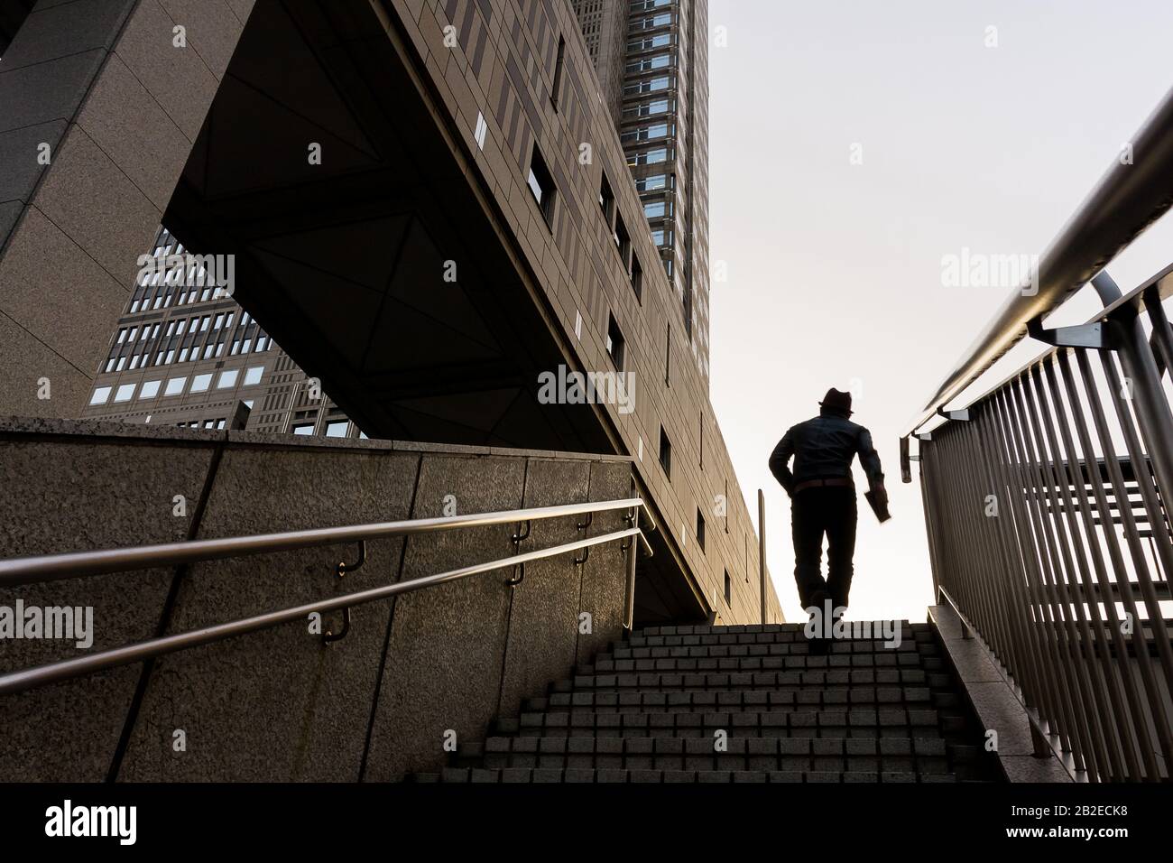 Ein Mann in Silhouette steigt einige Schritte in der Nähe eines Teils des Tokyo Metropolitan Government Building in Shinjuku, Tokio, Japan, hinauf. Stockfoto