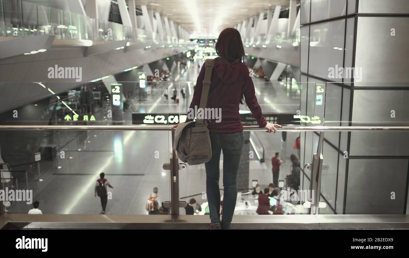 Frauen Auf Dem Stand Blick auf Die Moderne Airport Hall. Kamera-Pan zum kaukasischen Mädchen mit Schultertasche. Vielbefahrene Internationale Terminals. Boarding Gate Sign, People Rush Rack Focus. Stockfoto