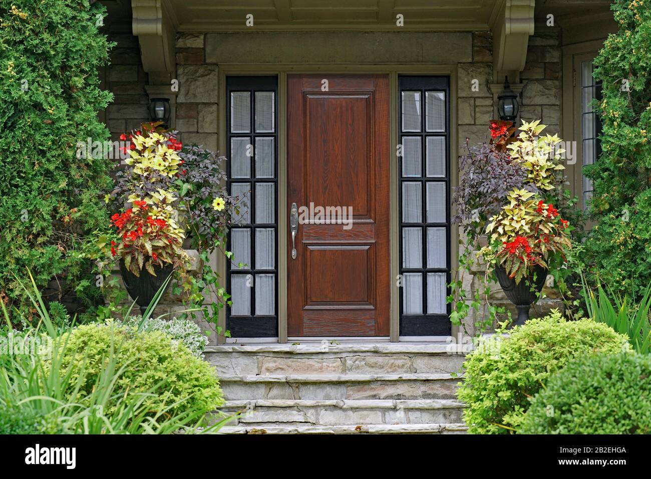 Holzfront des alten Steinhauses mit Blumen und Zedernbüschen Stockfoto