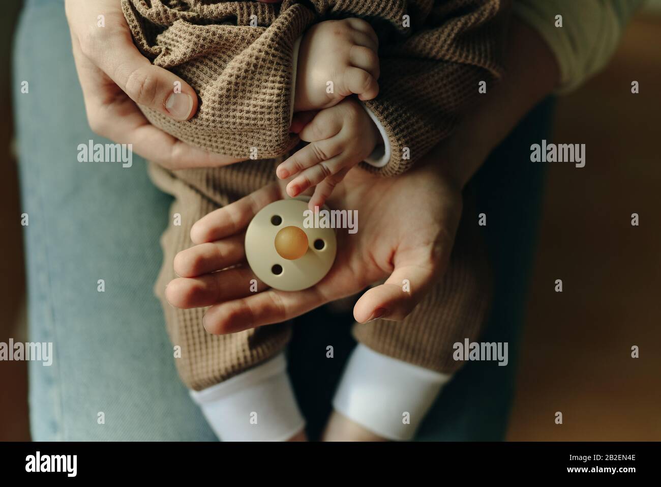 Baby hält einen Schnuller in den Armen seiner Mutter Stockfoto