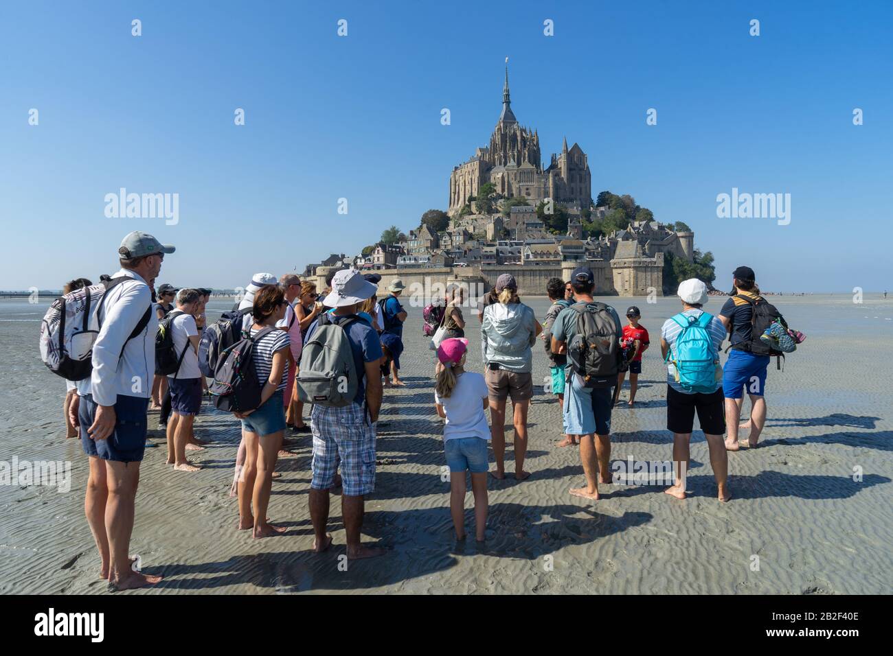 Menschen, die auf Sand spazieren, um Die Bucht Am Mont-Saint Michel, Normandie, Frankreich zu Überqueren Stockfoto