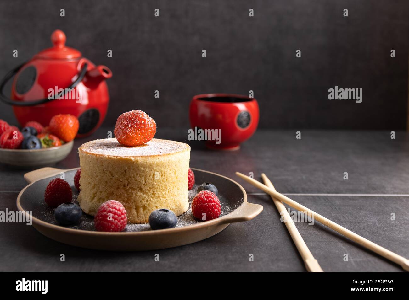 Hausgemachte japanische Hotcakes auf Holzgrund mit Himbeeren, Brombeeren und Erdbeeren und Zuckerpulver. Stockfoto